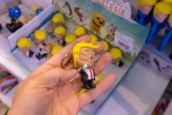 Donald Trump als Schlüsselanhänger in schimpfender Haltung in einer Hand gehalten
