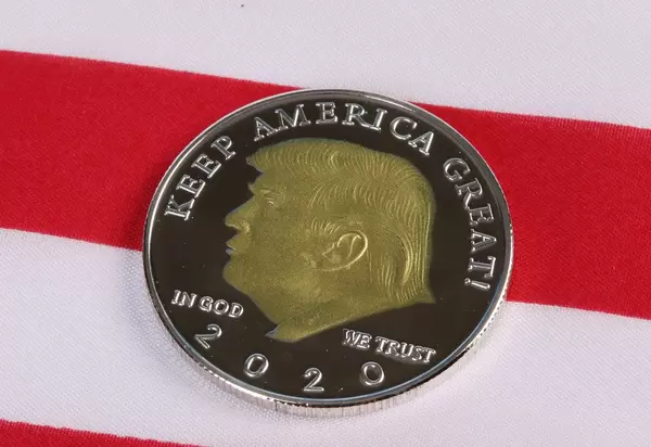 Donald Trump on a coin against American flag