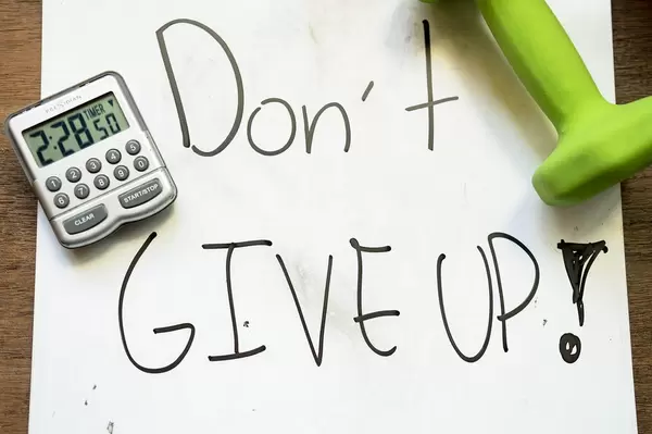 DON'T GIVE UP Aufschrift unter einer Hantel und Stoppuhr für Interval Training
