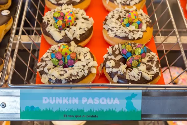 Donuts mit Schokoglasur und Kokosrasplen "Dunkin Pasqua" verziert mit Osterschmuck in Barcelona, Spanien