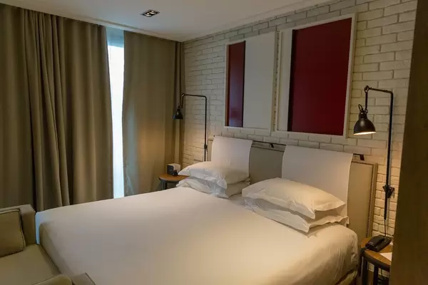 Doppelbett mit weißem Laken im Hotelzimmer des "The Corner Hotel" nahe des Plaça del Doctor Letamendi Parks in Barcelona, Spanien