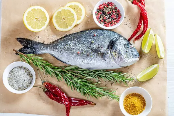 Dorado fish is prepared for baking on parchment paper with ingredients (Flip 2019)