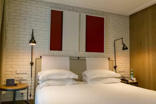 Double bed with white sheets and brick wall in the hotel room of "The Corner Hotel" near the Plaça del Doctor Letamendi Park in Barcelona, Spain