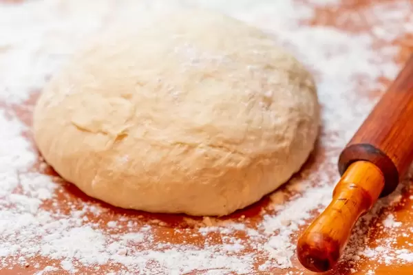 Dough with flour, rolling pin on wooden table