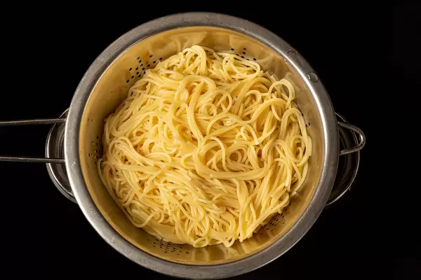 Draining hot, cooked spaghetti in a colander, top view