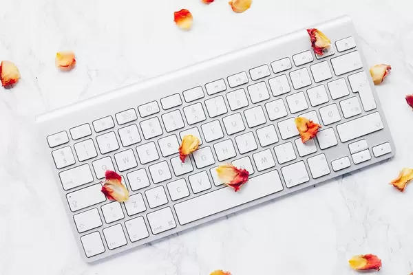 Draufsicht einer Tastatur mit Blütenblättern einer Rose auf Marmor