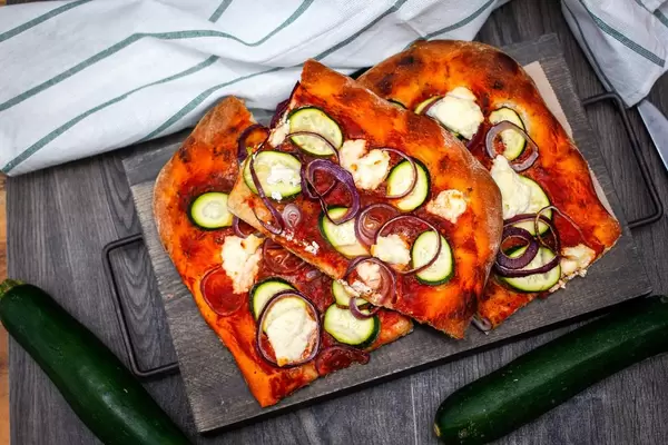 Draufsicht einer vegetarischen Pizza mit Zucchini und roten Zwiebeln