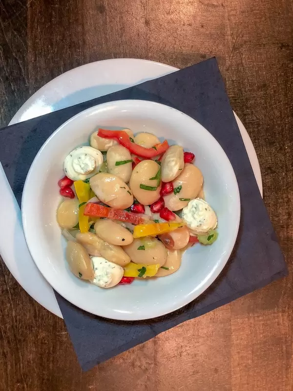 Draufsicht eines Elefantenbohnen-Salates mit Granatapfel und Ziegenkäsecreme