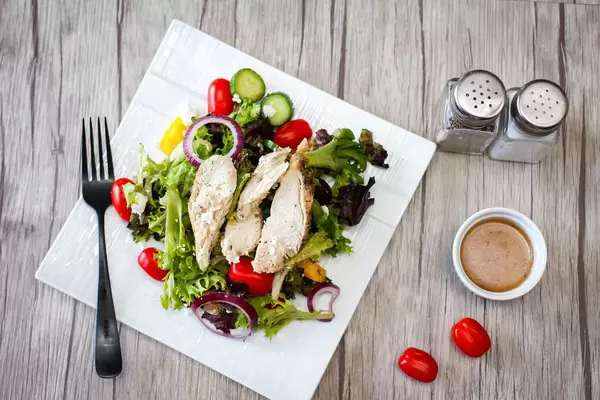 Draufsicht eines Geflügelsalates mit Cherrytomaten, Gurken und Blattsalat