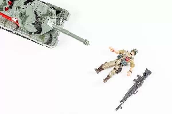 Draufsicht Panzer und Spielfigur eines auf dem Boden liegenden Soldaten auf weißem Hintergrund - Konzept des Todes