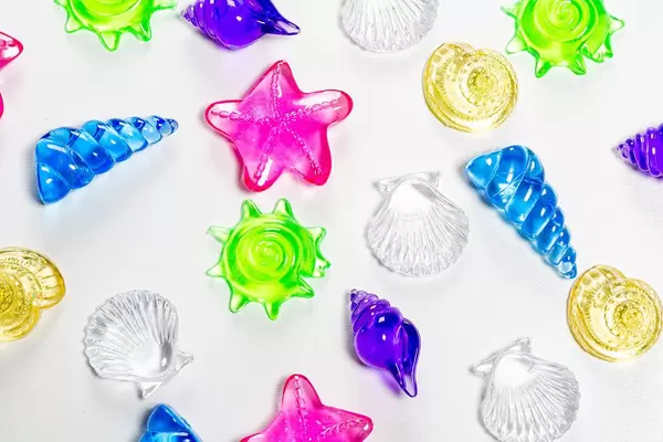 Draufsicht von bunten Muscheln auf weissem Hintergrund - Dekoration für das Aquarium