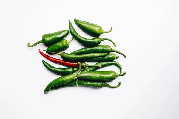 Draufsicht von grünen und roten Chilischoten vor weißem Hintergrund