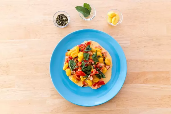 Draufsicht von Kürbisgnocchi in Paprikasoße und Zutaten in kleinen Schalen