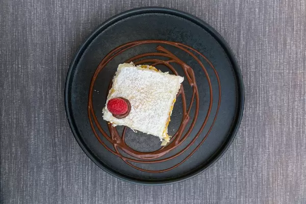 Draufsicht von rundem schwarzem Teller mit Pfirsich-Sahne Mille-feuille bei Villa Vegana auf Mallorca