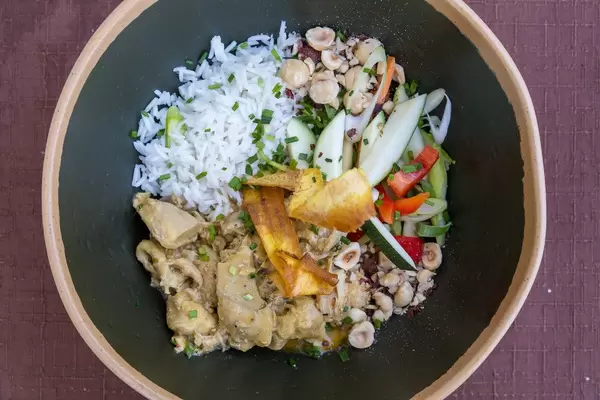 Draufsicht von schwarzer Schüssel mit Curry-Huhn, Reis und saisonalem Gemüse bei Q11 auf Mallorca