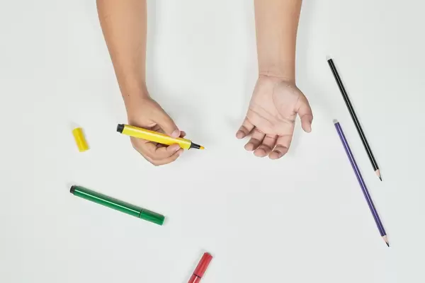 Drawing classes. Boy holding a yellow marker. View from directly above