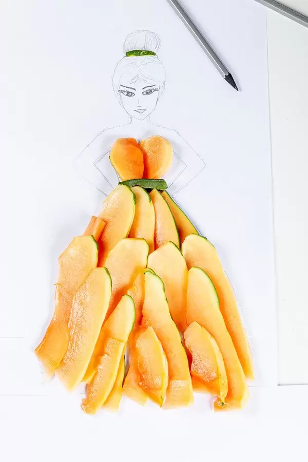 Drawing - sketch of a girl in a dress made of papaya slices on a white background with pencils