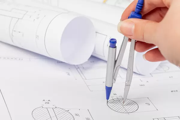 Drawings on the table and drawings in rolls, a female hand holds a compass