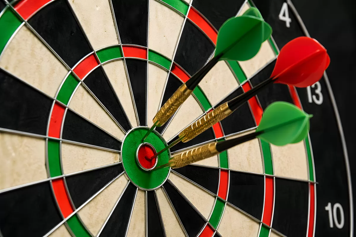 Drei Dartpfeile treffen das Bullseye auf Dartscheibe