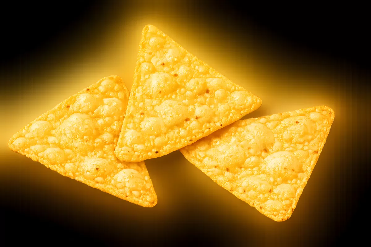 Drei goldene Tortilla-Chips vor dunklem Hintergrund
