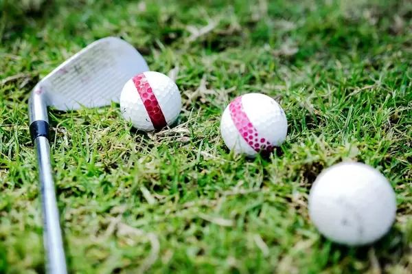 Drei Golfbälle und eine Golfschläger auf dem Grün