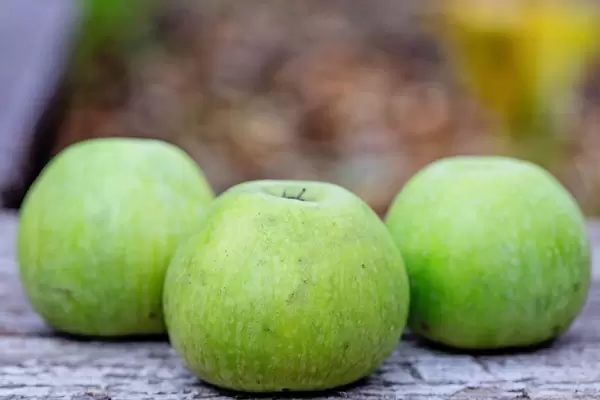Drei grüne Äpfel auf einem Holztisch