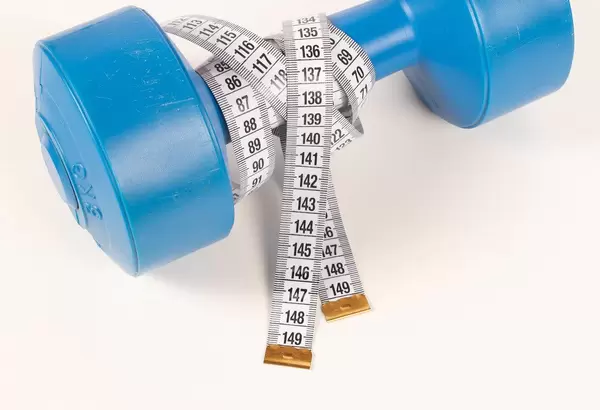 Drei Kilo Fitnesshantel mit einem weißen Maßband auf weißem Untergrund