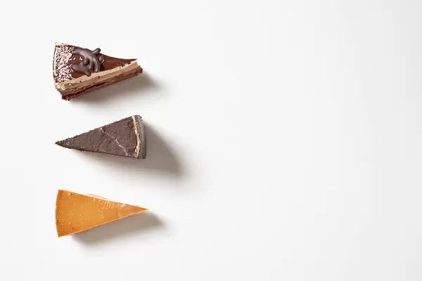 Drei Portionen Torte aus der Konditorei vor weißem Hintergrund mit Platz für Text rechts