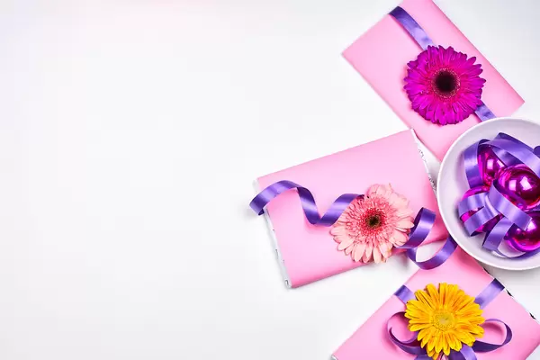 Drei rosa Geschenke mit Blumen, lila Schleife und Weihnachtskugeln mit Platz für Text links
