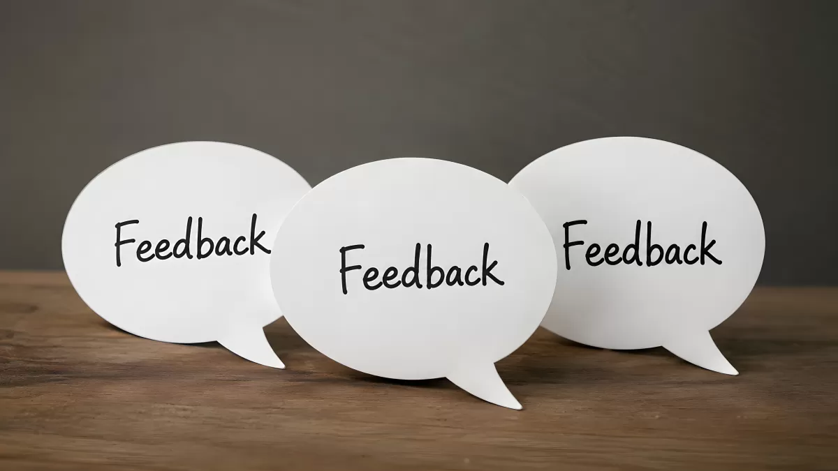 Drei Sprechblasen mit Feedback-Aufschrift auf Holztisch