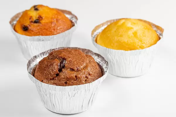 Drei verschiedene Muffins mit unterschiedlichen Füllungen, vor weißem Hintergrund