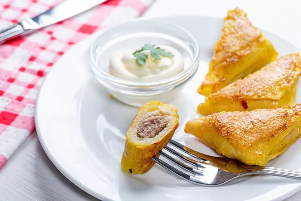 Dreieckig-geformte Pfannkuchen, frittiert, mit Hack gefüllt