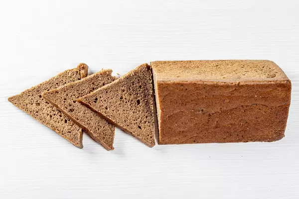 Dreieckig geformtes Roggenbrot auf weißem Holztisch