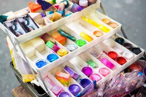 Dreistöckige Box mit Set aus Theaterschminke, bestehend aus bunter Gesichtsfarbe, Schwämmen, künstlichen Wimpern und Strasssteinen