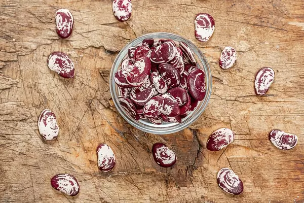 Dried beans in a glass bowl on an old wooden background. Top view