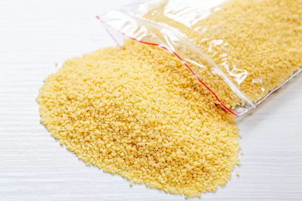 Dried couscous seeds on white wooden background