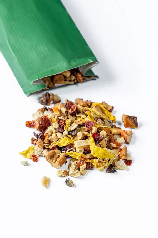 Dried fruit and flower tea spilled from the package on a white background
