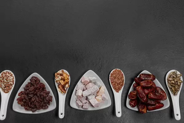 Dried fruits, nuts and seeds on a black background with free space. Healthy food concept