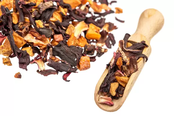 Dried hibiscus petals with dried fruits on a white background with a wooden scoop