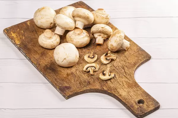 Dried mushroom slices and fresh mushrooms on old kitchen board