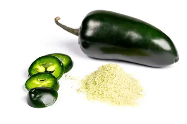 Dried powder and fresh jalapeno pepper on white