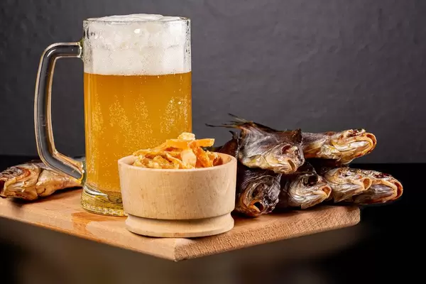 Dried roach fish and tuna with a glass of unfiltered beer