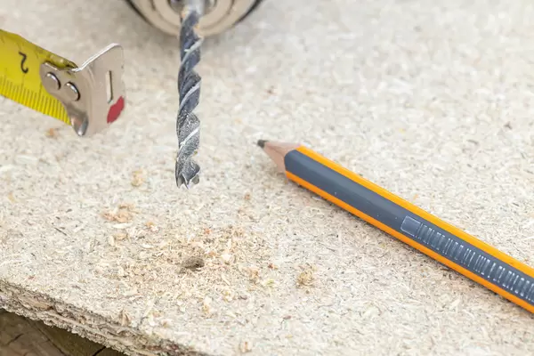 Drilled hole on the plywood with tape measure and pencil