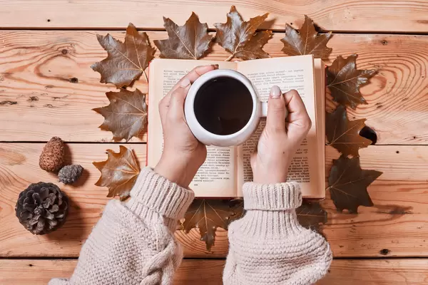 Drinking hot coffee in a cold autumn morning and reading a book