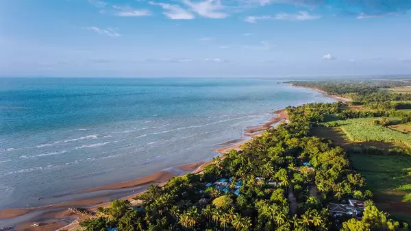 Drohnenaufnahme der Küste von Hinigaran mit braunem Sandstrand und grünem Hinterland, Insel Negros, Philippinen