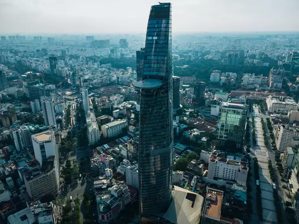 Drohnenaufnahme vom Bitexco Financial Tower mit Helikopter Landefläche neben der leeren Nguyen Hue Fußgängerzone und dem Ben Thanh Markt im Hintergrund in Ho Chi Minh Stadt, Vietnam