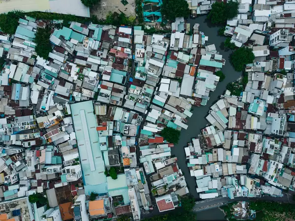 Drohnenaufnahme von Häusern in einem Wohngebiet neben einem kleinen Fluss in der Vogelperspektive in Ho Chi Minh Stadt, Vietnam