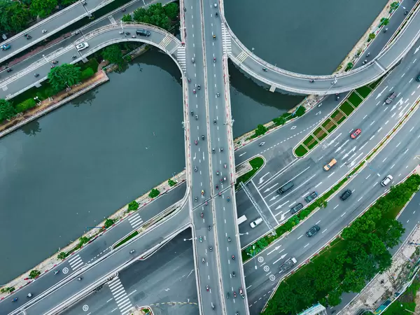 Drohnenaufnahme von Motorrollern und Autos auf einer Brücke über dem Saigon Fluss und einer Autobahn in Ho Chi Minh Stadt, Vietnam
