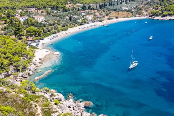 Drohnenbild mit Blick von Bekiri's Höhle auf die Bucht am Saint Anargyri Beach, mit Segelbooten und Urlaubern