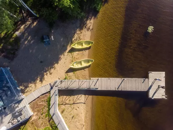 Drohnenbild von einem Holzsteg vor dem Gästehaus Villa Jolla, mit grünen Ruderbooten am Seeufer Päijänne, zwischen Lahti und Jyväskylä